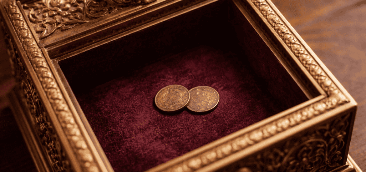 Two small coins in the bottom of an ornate wooden box that is lined in velvet